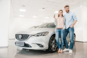 a man and a woman standing next to a car